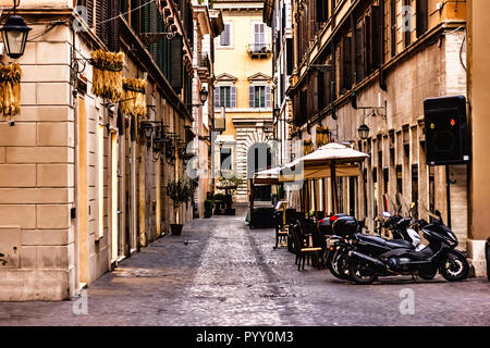 Les scooters et un café de la rue dans une étroite rue typique de Rome Banque D'Images