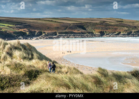 Les gens qui marchent à travers l'Ammophila Ammophile sur le système de dunes de sable donnant sur plage de Crantock en Newquay en Cornouailles. Banque D'Images