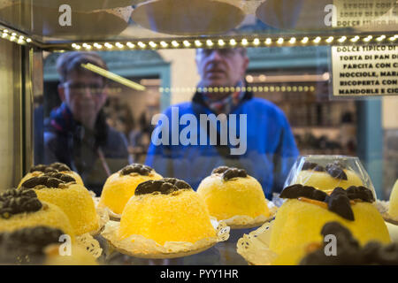 Les touristes ressemble à travers une vitre desserts typiques appelés "Polenta e Osei'. Vieille ville de Bergame, Bergamo province, Lombardie, Italie. Banque D'Images