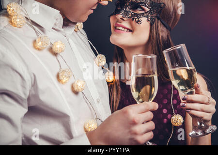 Les jeunes couples célébrant le Nouvel An drinking champagne on masquerade party Banque D'Images