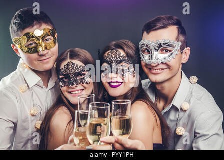 Couples célébrant le Nouvel An drinking champagne on the masquerade party Banque D'Images