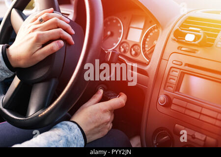 Jeune femme de faire démarrer le moteur dans sa voiture. Close up l'intérieur de la voiture. Banque D'Images