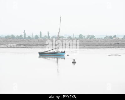 Bateau à voile bleu sur le bassin de l'estuaire à Heybridge misty Nr Maldon, Essex Banque D'Images