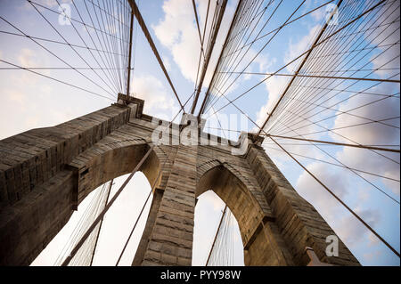 Close-up abstraite de la tour en pierre et de passage de câbles de suspension en acier du pont de Brooklyn sous un ciel coucher de soleil pittoresque Banque D'Images