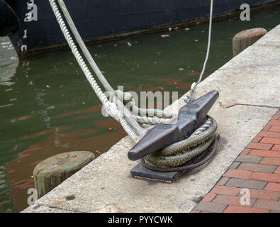 Des cordes à partir d'un bateau amarré à un crochet d'attelage sur une zone portuaire sale Banque D'Images