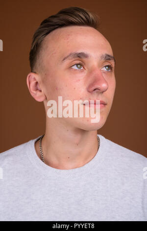 Beau jeune homme aux cheveux blonds contre fond brun Banque D'Images