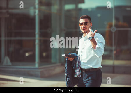 Un jeune homme est dans la rue, marcher, s'amuser et montrant le rocher signe avec ses mains Banque D'Images