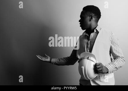 Jeune homme africain construction worker montrant quelque chose de noir Banque D'Images