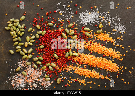 Lentilles sèches et de soja avec poivre et sel rouge rock éparpillés sur fond naturel de l'ardoise Banque D'Images