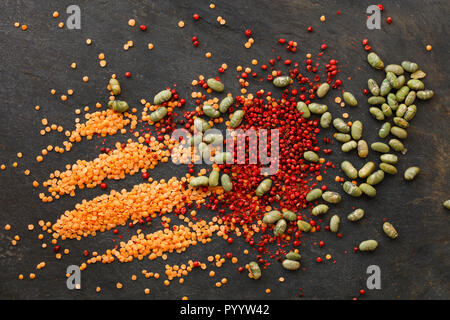 Lentilles sèches et de soja avec poivre rouge éparpillés sur fond naturel de l'ardoise Banque D'Images