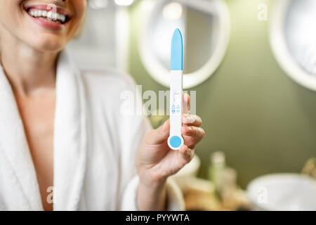 Happy woman holding stick test de grossesse dans la salle de bains. Vue rapprochée sur le stick Banque D'Images