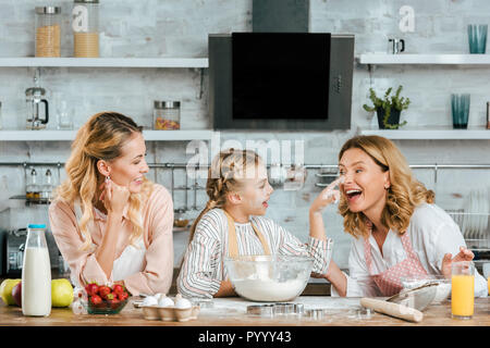 Heureux petit enfant préparer la pâte et la jouer avec mère et grand-mère à la maison Banque D'Images