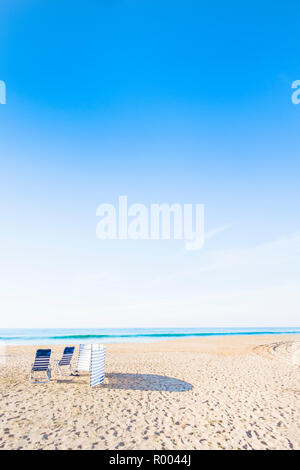 Chaises bleu et blanc et à l'abri du vent plage déserte Banque D'Images