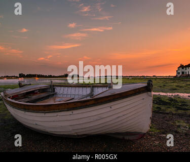 Une vieille barque en bois blanc au fond de la mer à marée basse pendant le coucher du soleil Banque D'Images