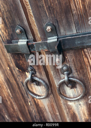 Libre d'un verrou en métal sur une vieille porte en bois. Poignées de porte en la forme d'anneaux Banque D'Images