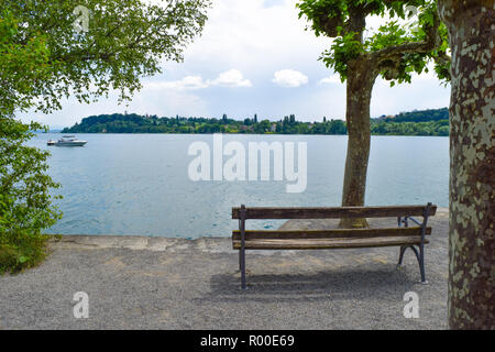 Île de Mainau vue à travers les arbres sur le lac de Constance Bodensee, banc, face au lac de l'île et ciel bleu Banque D'Images