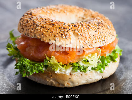 Frais sain sandwich Bagel au saumon, ricotta et de laitue dans la plaque noire sur fond noir table de cuisine. Banque D'Images