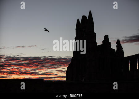 Whitby, Yorkshire, UK : 25 octobre 2018. Lever du Soleil contre les ruines de l'abbaye de Whitby comme la ville Banque D'Images