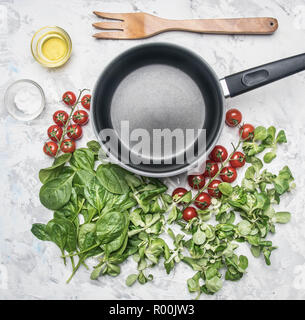 Concept de la cuisson de la nourriture végétarienne, tomates cerises, diverses variétés de salades, les assaisonnements, les épices, l'huile d'olive, bordée autour du poêle vintage Banque D'Images