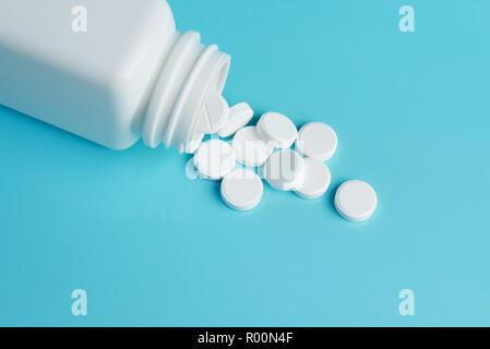 Flacon de médicaments et pilules blanches renversé sur fond de couleur bleue. Médicaments et prescription pills arrière-plan. Les médicaments pharmaceutiques. Banque D'Images