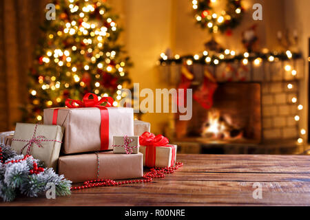 Des cadeaux de Noël sur la table en bois sapin décoré et cheminée concept vacances hiver Banque D'Images