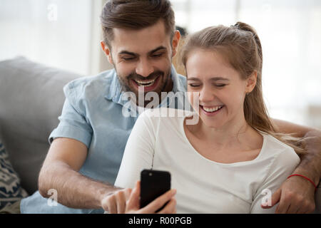 Couple sitting on couch using mobile phone Banque D'Images