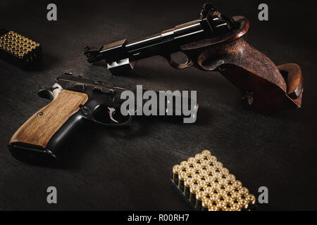 Pistolets noir et des balles sur une table en bois noir Banque D'Images