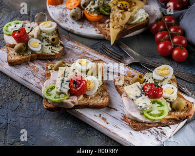 Toasts appétissants de l'avocat, viande, œufs de caille, tomates et fromage bleu Dor. La cuisine de l'auteur. Servant des plats originaux Banque D'Images