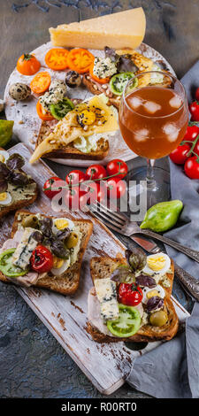 Délicieux toasts à l'avocat, oeufs de caille, tomates, fromage bleu Dor et un verre de vin blanc froid. La cuisine de l'auteur. Servant des plats originaux Banque D'Images