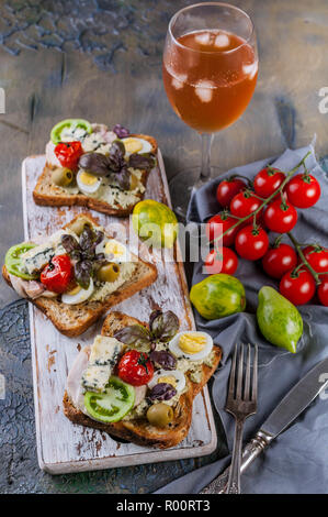 Délicieux toasts à l'avocat, oeufs de caille, tomates, fromage bleu Dor et un verre de vin blanc froid. La cuisine de l'auteur. Servant des plats originaux Banque D'Images