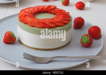 Démonstration de cuisine. Sans cuisson deux couches mini cheesecake matcha fraisier. Coupes de fraises décorer le dessus du gâteau. 3 tasses à café, biscuits et s Banque D'Images