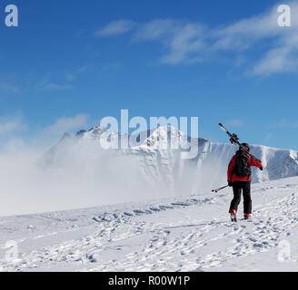 Avec skieur skis sur l'épaule aller jusqu'en haut de la montagne dans le froid journée ensoleillée. Dans le brouillard d'hiver montagnes du Caucase, la Géorgie, la région Gudauri, Mt. Kudebi. Banque D'Images