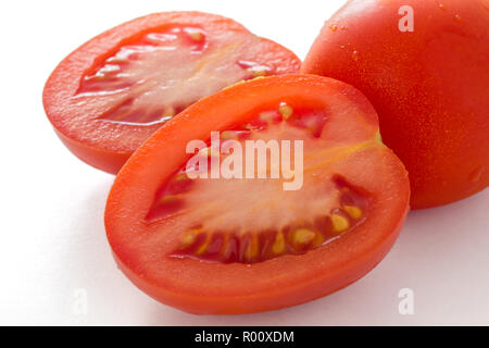 Tomate prune rouge coupé en deux sur la surface blanche Banque D'Images