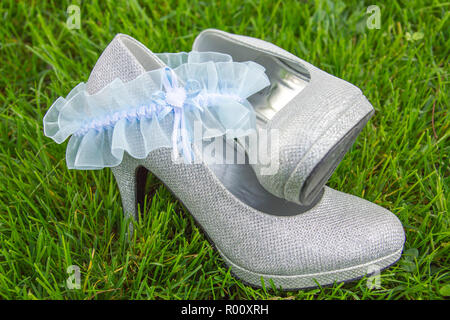 Light blue porte-jarretelles avec de l'argent high heel shoes sitting in grass Banque D'Images