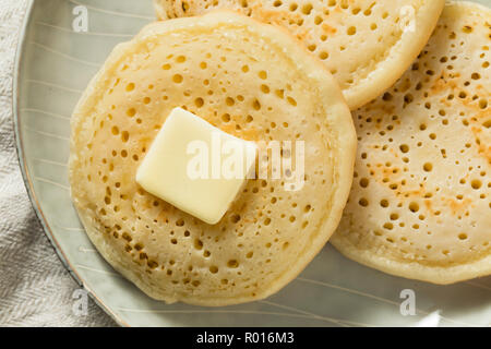 Des Crumpets britannique grillé avec du beurre pour le petit déjeuner Banque D'Images