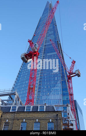 Le Shard, le plus haut bâtiment de la Grande-Bretagne, vue depuis le sol à proximité, avec deux très grandes grues à tour peint en rouge au premier plan. Banque D'Images