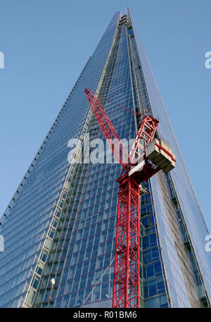 Le Shard, le plus haut bâtiment de la Grande-Bretagne, vue depuis le sol à proximité, avec deux très grandes grues à tour peint en rouge au premier plan. Banque D'Images