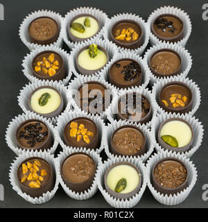 Bonbons de chocolat avec divers matériaux dans une enveloppe de papier sur un arrière-plan lumineux. Banque D'Images