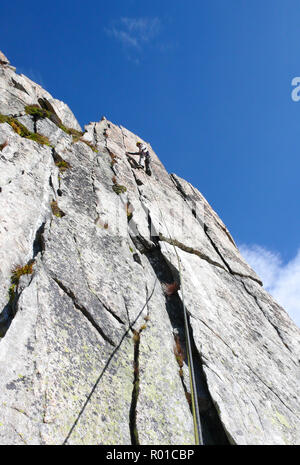 Guide de montagne alpiniste sur une route de granit raide dans les Alpes de Suisse sur une belle journée Banque D'Images