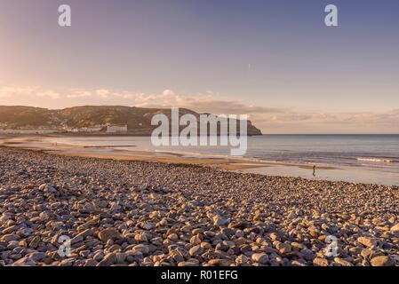 Une vue de courbée du Llandudno bordé par des rives hôtels rieuses au crépuscule. Le grand orme pointe est dans la distance et d'une décoloration blue sky est ab Banque D'Images