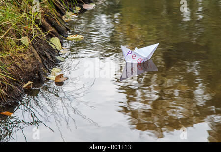 Papier blanc solitaire appelé bateau flottant sur un ruisseau de paix outdoor le jour d'automne closeup Banque D'Images