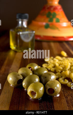 Olives vertes sur bois sain avec compteur Tajine rouge et bouteille d'huile Banque D'Images