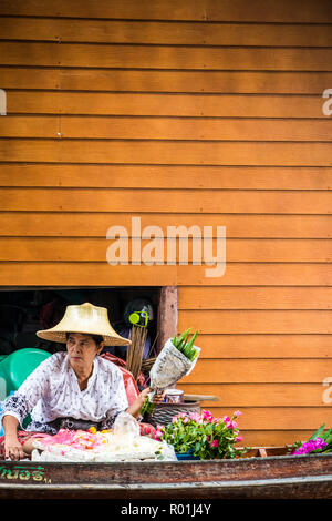 Damnoen Saduak, Thaïlande - 8 octobre 2018 : femme vendeuse de fleurs au marché flottant. Le marché est une destination touristique très poular. Banque D'Images