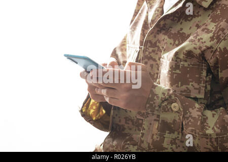 US Army. Jeune soldat holding a mobile phone debout sur fond blanc Banque D'Images