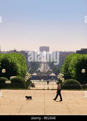 Un homme promène son chien sur l'axe Historique de l'Esplanade du Général de Gaulle, la Défense, Paris. Vue vers l'Arc de Triomphe et la Place de l'Étoile Banque D'Images