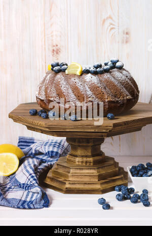 Gâteau bundt citron fait maison avec des bleuets sur support en bois. Banque D'Images