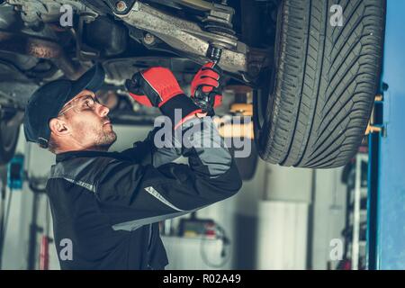 Caucasian Mécanicien de voiture Réglage de la tension dans l'élément de suspension du véhicule. Professionnels du Service. Banque D'Images