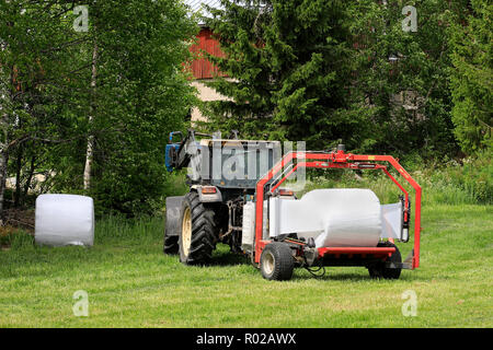 Uurainen, Finlande - le 15 juin 2018 : Wrapping hay bales in plastic film avec Lamborghini tracteur Vicon et BV 1700 wrapper par satellite le jour de l'été. Banque D'Images