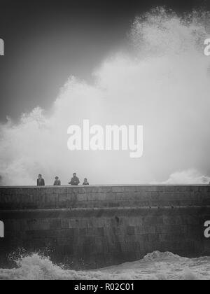 Porto, Portugal - 7 Février 2016 : Les personnes qui traversent le fleuve Douro dangereuses bouche vieux pilier sud au cours d'une tempête en mer. Banque D'Images