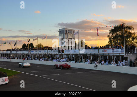 Sunset soir crépuscule course automobile vintage au Goodwood Revival. Course de voiture d'endurance. Voitures de course en ligne droite, stands droit Banque D'Images